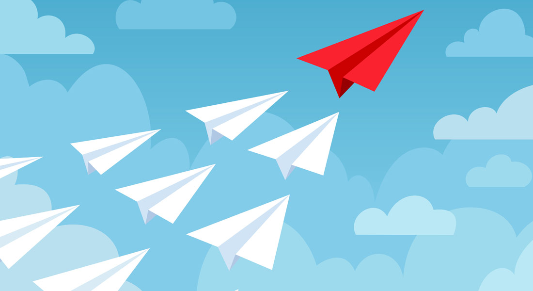 A red paper airplane leading white paper planes into the sky